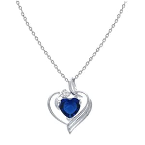 A delicate silver necklace features a heart-shaped pendant with a blue stone and a small clear stone accent, all set on a thin chain.