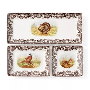 A set of three rectangular plates with floral borders and wildlife illustrations, featuring a turkey, pheasants, and a quail.