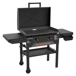 Blackstone 28\“ Omnivore Grill features a flat griddle with two burners, side shelves, and a removable grease tray, all on a wheeled cart. It includes a hinged lid for versatile cooking options.