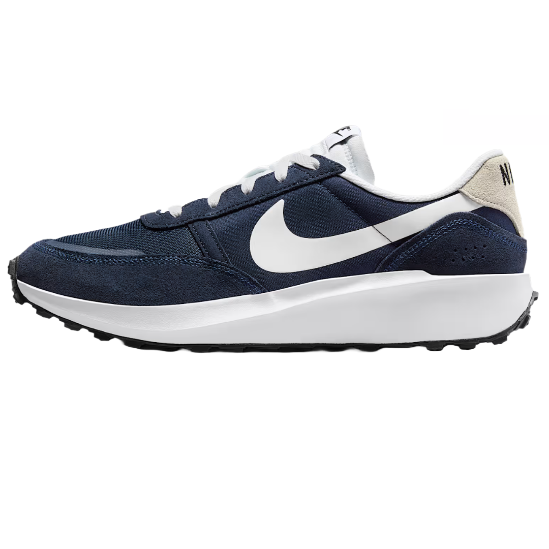 Nike Men's Waffle features a navy blue and white color scheme with a suede and mesh upper, white midsole, and black waffle outsole, showcasing a classic white Swoosh logo on the side.