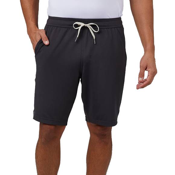A person is wearing black drawstring shorts paired with a white shirt, with one hand in the shorts' pocket.