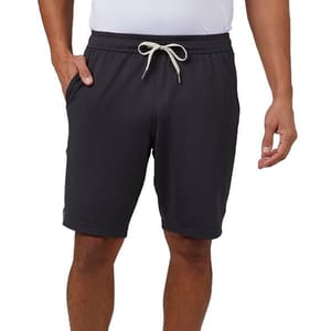 A person is wearing black drawstring shorts paired with a white shirt, with one hand in the shorts' pocket.