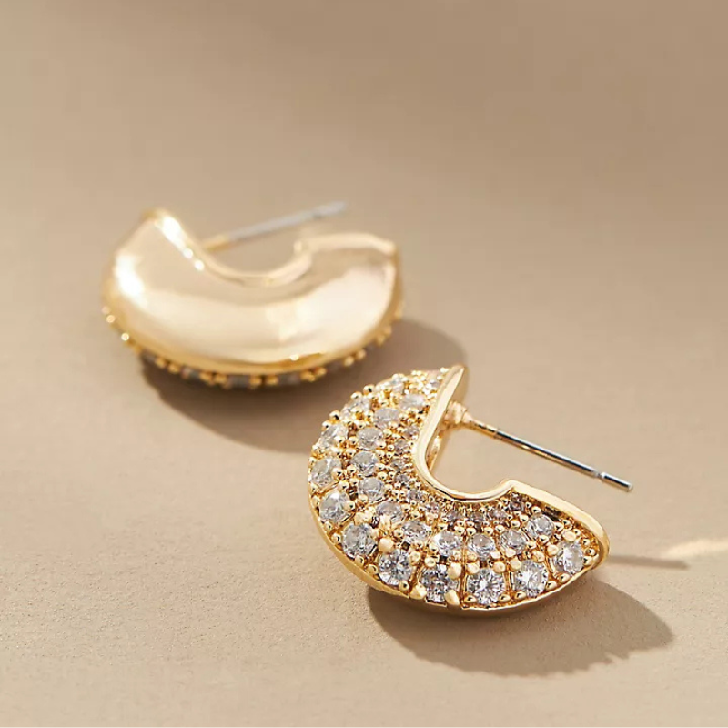 Gold-tone pavé half-circle hoop earrings adorned with sparkling clear stones, creating a luxurious and elegant look.