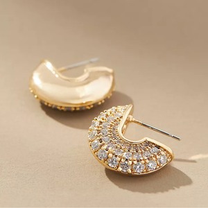 Gold-tone pavé half-circle hoop earrings adorned with sparkling clear stones, creating a luxurious and elegant look.