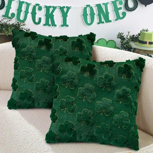 Two dark green throw pillows with textured shamrock patterns on a beige sofa, with a \“LUCKY ONE\“ banner in the background.