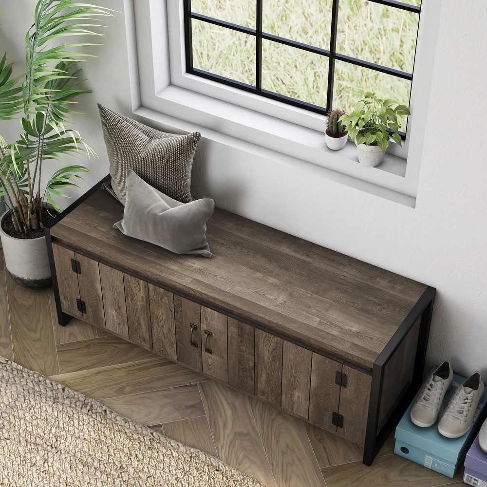 The Oak 49\“ Iron Legs Storage Bench features a rustic wooden design with dual doors and black metal legs, offering storage and a surface for seating. Two decorative pillows are placed on top, and shoes are stored underneath.