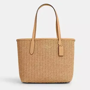 A beige woven tote bag with tan leather handles.