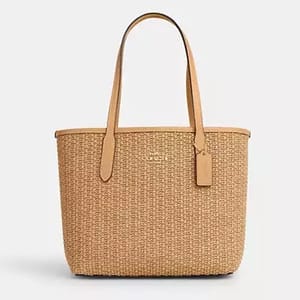 A beige woven tote bag with tan leather handles.