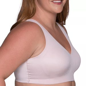 A woman is wearing a light pink, seamless bra with wide straps and a V-shaped neckline.