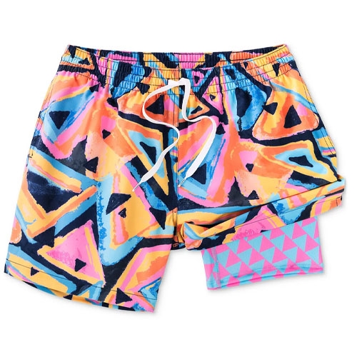 Colorful swim shorts with a 5.5-inch inseam, featuring a vibrant geometric pattern in orange, blue, pink, and black. They include a drawstring waistband and contrasting inner lining with a pink and blue triangle design.