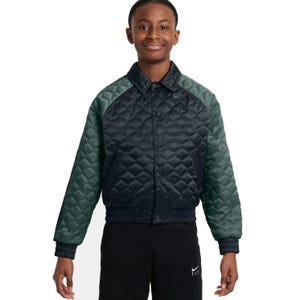 Dark quilted jacket with green sleeves and a subtle logo on the chest, worn by a person in black pants featuring a small logo.