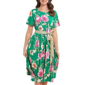A green floral dress with short sleeves, featuring a pink and white flower pattern and a beige tie belt at the waist.