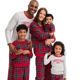 Family wearing matching Christmas-themed pajamas, featuring red plaid designs and \“Christmas Crew\“ text.