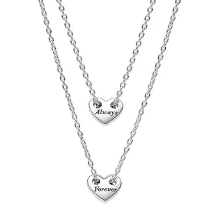 Two silver necklaces with heart-shaped pendants, one inscribed with \“Always\“ and the other with \“Forever\“. Each pendant is suspended from a delicate chain.