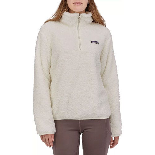A person wearing a fuzzy off-white quarter-zip fleece pullover and taupe leggings.