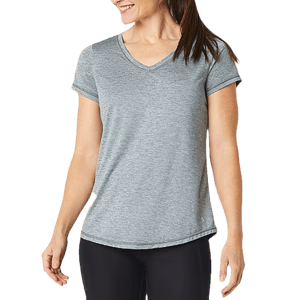 A woman is wearing a light gray, short-sleeve V-neck Xersion Performance Top paired with black leggings.