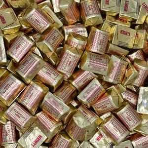 Hershey's Nuggets with Almonds, wrapped in gold foil and red lettering, are individually wrapped chocolates featuring almonds, packaged in a 5lb bulk assortment.