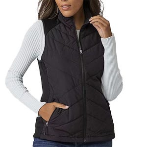 A woman wearing a black quilted zip-up vest over a white ribbed long-sleeve shirt, paired with blue jeans.
