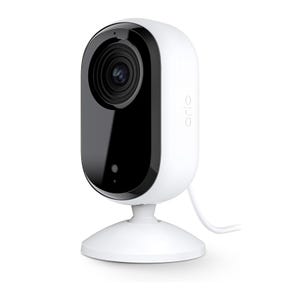 Arlo Essential Indoor Camera with a black front and white body, featuring a built-in stand and a power cable for indoor security use.