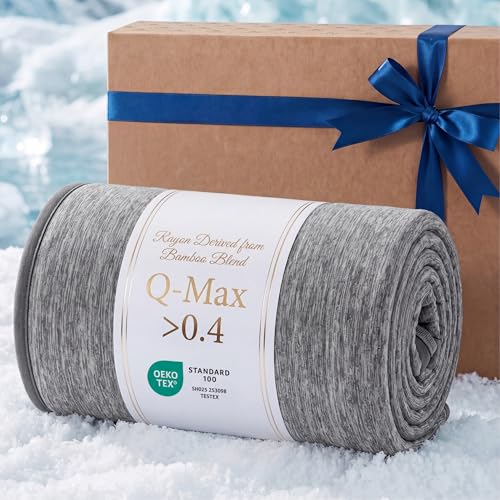 A gray bamboo blend blanket labeled \“Q-Max >0.4\“ with OEKO-TEX certification is rolled up on a snowy surface next to a brown gift box tied with a blue ribbon.