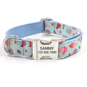 A light blue dog collar with colorful prints of ice cream, strawberries, and other treats. It features a silver buckle with engraved details reading \“SAMMY\“ and the phone number \“123 456 7890.\“