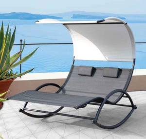 A double lounge chair with a curved frame and canopy, featuring two headrests, set on a terrace overlooking a body of water, accompanied by a potted plant.