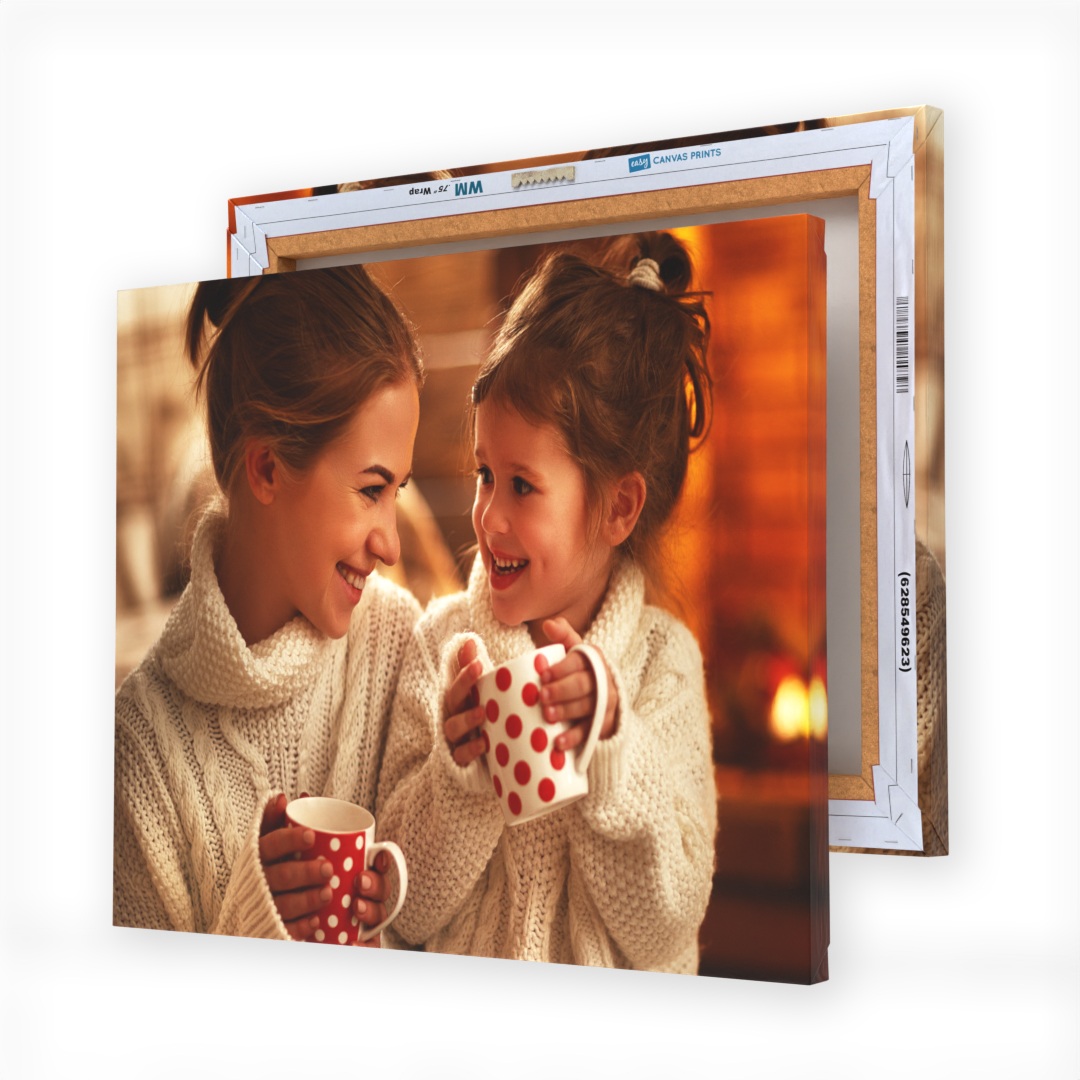 Two stacked canvas prints featuring a mother and daughter, both smiling and holding polka-dotted mugs, dressed in cozy sweaters against a warm, indoor background.