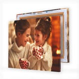 Two stacked canvas prints featuring a mother and daughter, both smiling and holding polka-dotted mugs, dressed in cozy sweaters against a warm, indoor background.