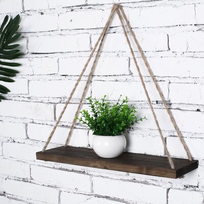 Two triangular rope-hung wooden shelves against a white brick wall, one with a potted plant.
