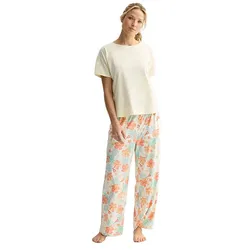 A woman wears a cream short-sleeve top paired with floral-patterned wide-leg pajama pants in pastel colors.
