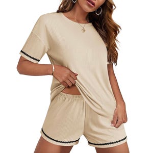 A beige ribbed lounge set featuring a short-sleeve top and elastic waist shorts with black scalloped trim on the sleeves and shorts.