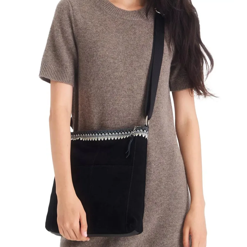 Woman wearing a brown short-sleeve dress and carrying a black crossbody bag with a decorative pattern at the top.