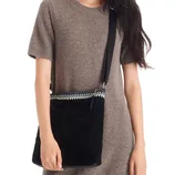 Woman wearing a brown short-sleeve dress and carrying a black crossbody bag with a decorative pattern at the top.