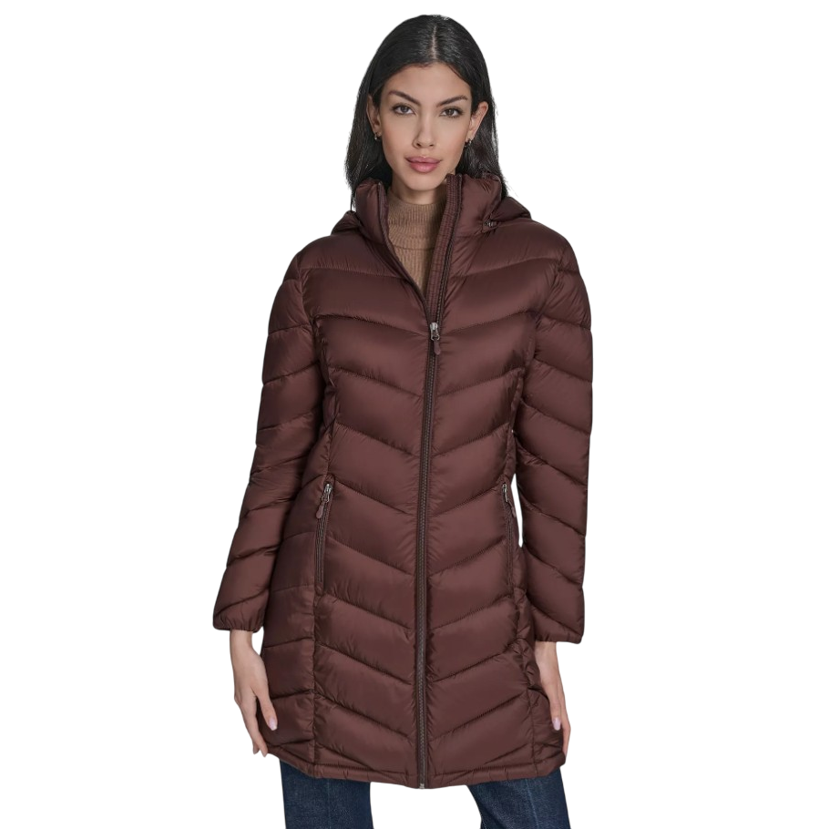 A woman is wearing a brown, quilted puffer coat with a hood and front zipper closure, paired with a brown turtleneck and blue jeans.