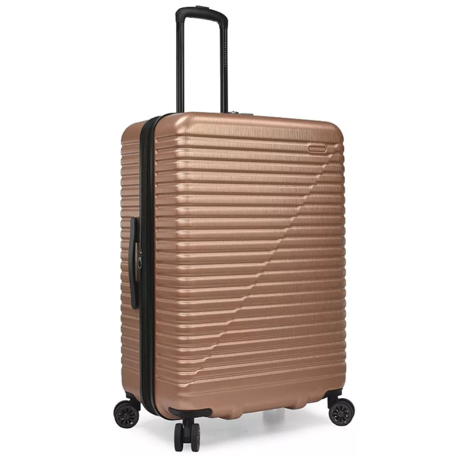 A large, rose gold hard-shell suitcase with a telescopic handle and four spinner wheels, featuring horizontal ridges and a side handle for easy carrying.