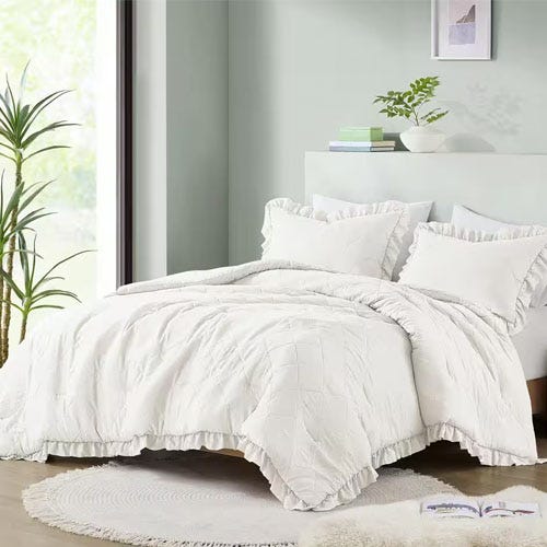 White bedding set with ruffled design, including a duvet cover and matching pillow shams on a bed.