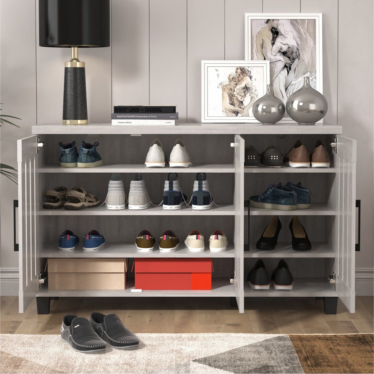 A modern shoe cabinet with a variety of shoes, boxes, and decor items on top, including a lamp, books, vases, and framed art pieces.