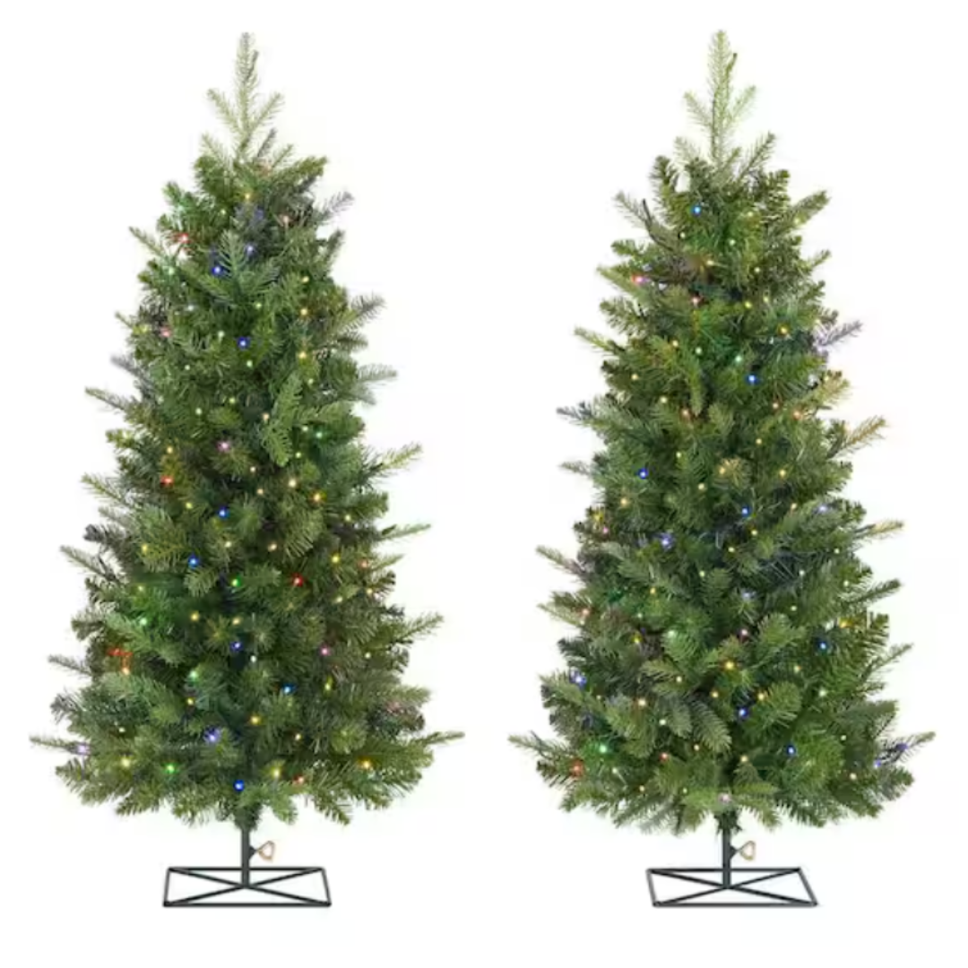 Two pre-lit artificial Christmas trees with multi-colored lights on metal stands.