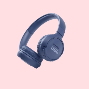 A pair of blue JBL over-ear wireless headphones on a pink background.
