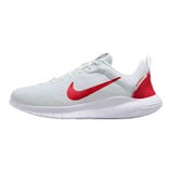 A white athletic sneaker with a red Nike swoosh and red accents on the heel, featuring a lightweight mesh upper and a cushioned white sole.