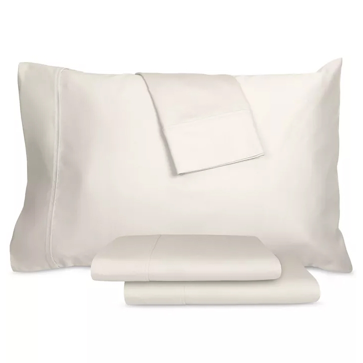 A set of cream-colored bedding items, including a pillowcase and folded sheets, displayed together.