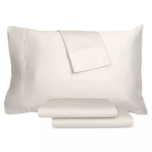 A set of cream-colored bedding items, including a pillowcase and folded sheets, displayed together.
