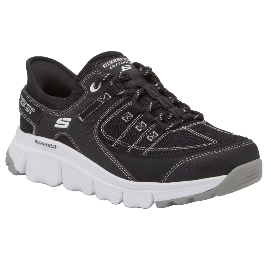 A black Skechers athletic shoe with white accents and laces, featuring a thick white and gray sole.