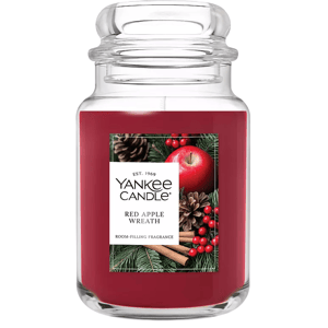 Yankee Candle jar with \“Red Apple Wreath\“ fragrance, featuring a holiday-themed label with an apple, cinnamon sticks, pine cones, and berries.
