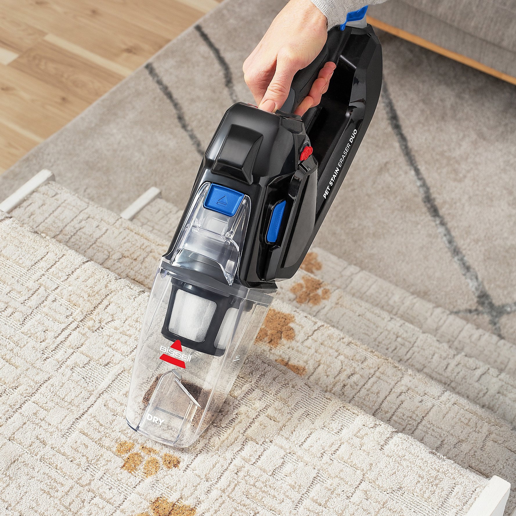 A handheld vacuum cleaner is being used to clean a carpet.