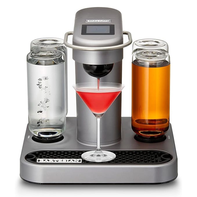 A countertop cocktail machine with three clear liquid containers and a central spout dispensing a red drink into a martini glass.