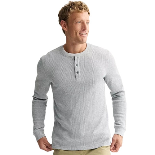 A man is wearing a light gray long-sleeve waffle-knit henley shirt with three buttons.