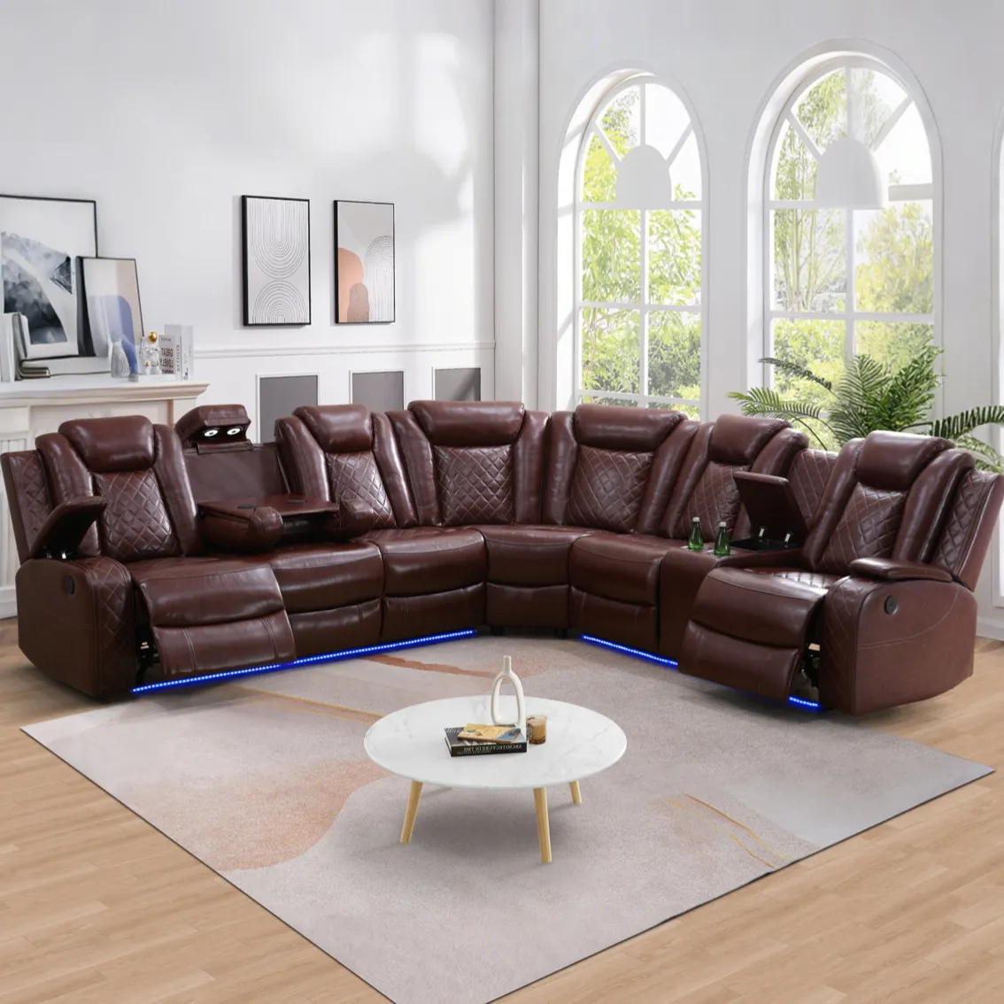 Brown leather sectional sofa with built-in recliners, cup holders, and LED lighting, set in a living room with large arched windows and a round marble coffee table.