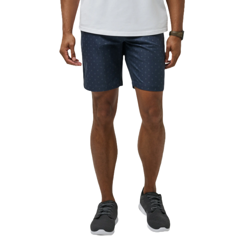 Navy blue flat front shorts with a subtle dotted pattern, worn above the knees. Paired with a white shirt and gray sneakers.