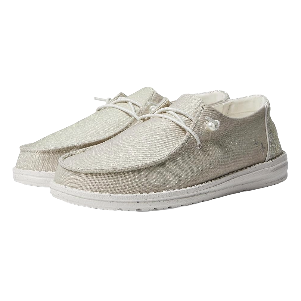 The Hey Dude Wendy Celestial Shine Shoes are lightweight casual slip-ons featuring a shimmering beige fabric upper with white laces and soles, designed for comfort and versatility.